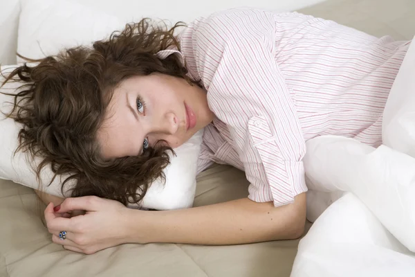 Bella donna bruna premurosa con un cuscino sul letto — Foto Stock