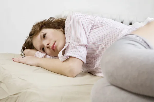 Brünette lockige Frau auf dem Bett liegend — Stockfoto