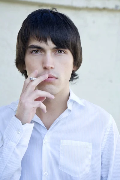 Young serious handsome smoking man to exhale smoke. — Stock Photo, Image