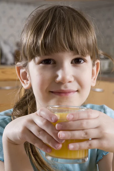 Kis aranyos, mosolygós lány hét éves narancs ital gyümölcslé — Stock Fotó