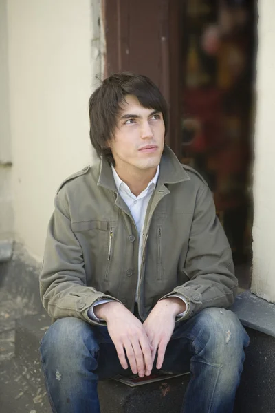 Retrato de un hombre guapo serio sentado en la puerta . — Foto de Stock