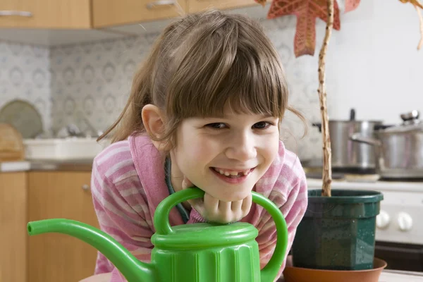 Niña de siete años con regadera sentada en la cocina —  Fotos de Stock