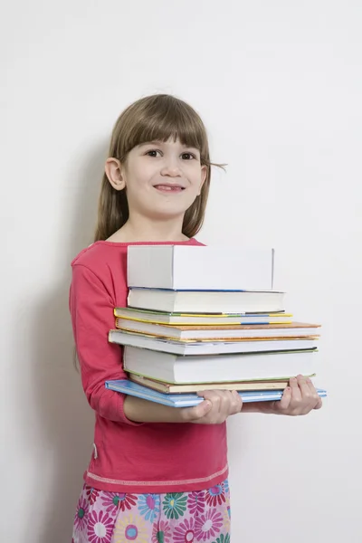 Little cute girl seven years old  carry books. White background — Stock Photo, Image