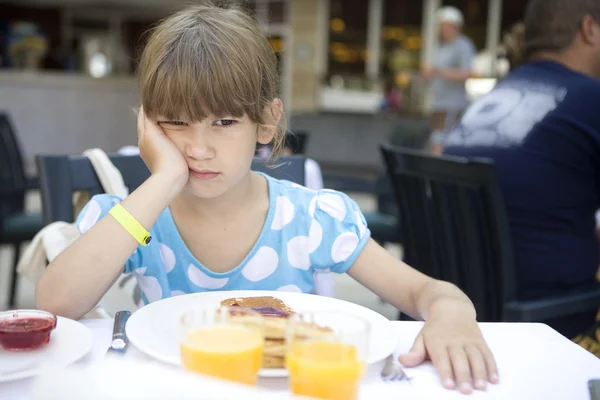 Meisje eet een pannenkoek voor het ontbijt. — Stockfoto