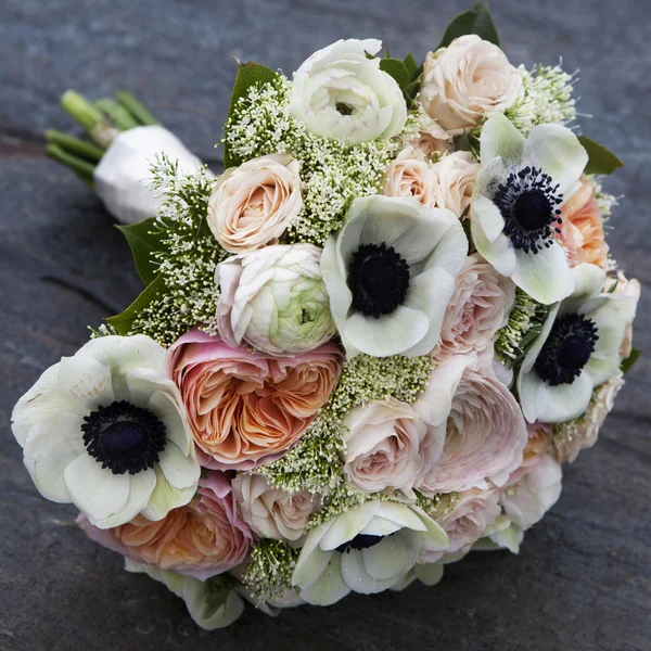 Wedding bouquet of pink roses and white anemone and pink ranunculus lying on wooden floor