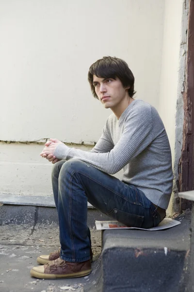 Serious handsome man sitting on on the doorstep. — Stock Photo, Image