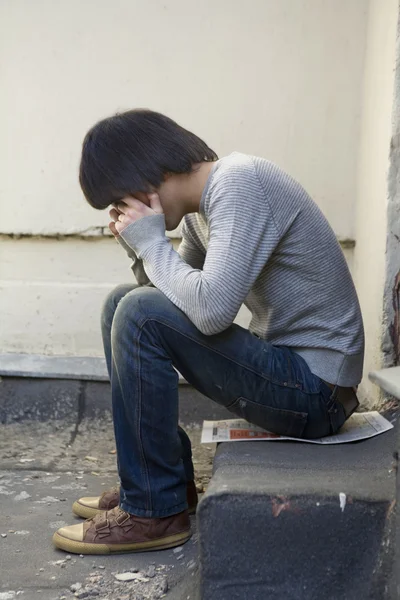 Ernster schöner Mann sitzt auf der Türschwelle. — Stockfoto