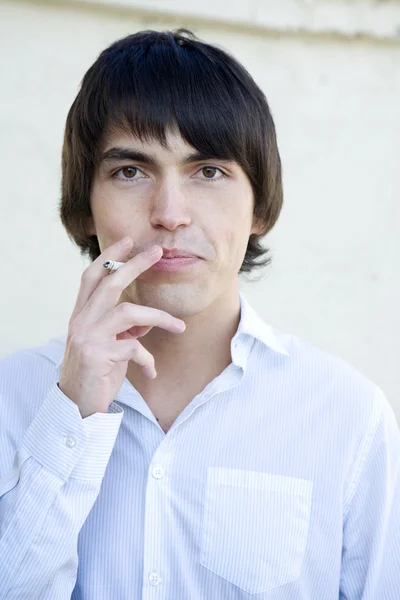 Young serious handsome smoking man to exhale smoke. — Stock Photo, Image