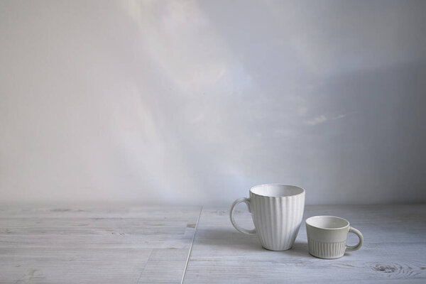 Minimalistic Scandinavian style. Two cups of coffee or tea of different sizes for two on on the table. Empty space.