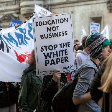 Londra, İngiltere - 19 Kasım 2017: Öğrenciler eğitim sistemindeki kesintilere ve ücretlere karşı bir protesto yürüyüşüne katıldılar. Genç bir adam bir poster tutuyor- Eğitim bir iş değildir. Beyaz kağıdı durdur.