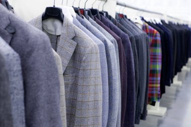 Gri, kareli, çizgili erkek tüvit ceketleri mağazada asılı duruyor. İş biçimi