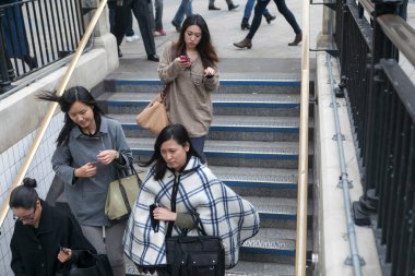 LONDON, ENGLAND - 19 Eylül 2021: 3 modaya uygun giyinmiş pançolu ve yağmurluklu kız Oxford Caddesi yakınlarındaki metro merdivenlerinden iniyor