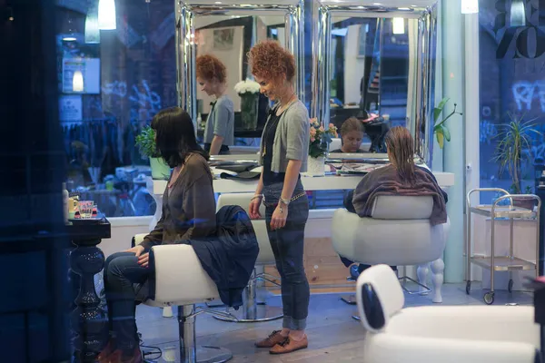 ロンドン イギリス 2017年11月19日 髪の毛の前に彼女のクライアントで鏡の中に赤い頭の巻きの女の子の美容師が見えます — ストック写真