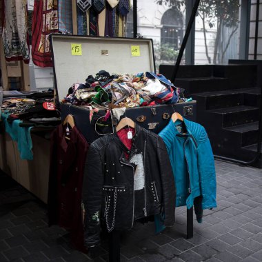 Londra, İngiltere - 15 Eylül 2021, tezgahta mavi ve siyah bir rockçı ceketi asılı. Spitalfields Antika Pazarında Satılık İpek Eşarplar Kutusu