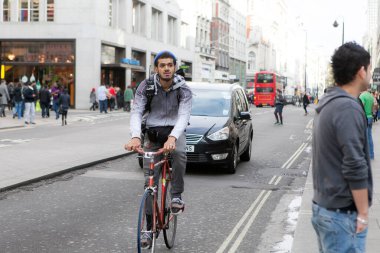 Londra, İngiltere - 19 Ekim 2021: Paltolu bir adam arabaların arasında bisiklet sürüyor