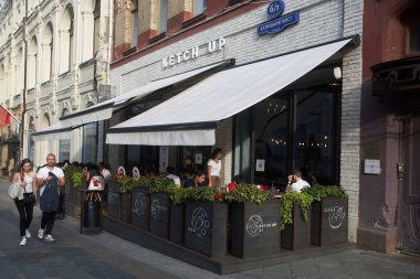 Moskova, Rusya - 31 Ağustos 2021, İnsanlar güneşli bir günde şehir merkezindeki bir verandada öğle yemeği yiyorlar. Kuznetsky Çoğu