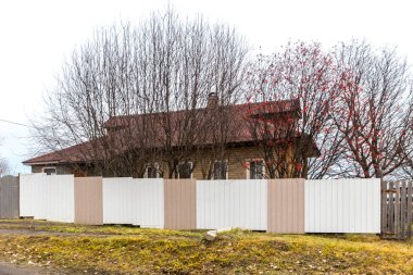 Kem, Karelia, Rusya, Kasım 2021 günbatımında demir renkli çitlerle çevrili beş duvarlı eski bir ahşap ev.