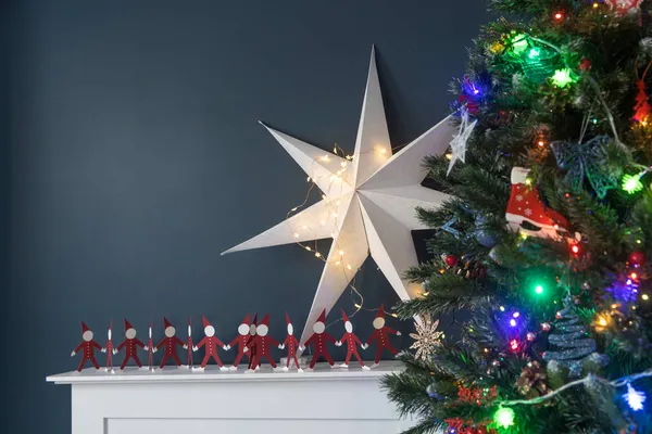 在圣诞树的后面 有一个人造壁炉 它的后面是一道深蓝色的墙 作为圣诞节的室内装饰 — 图库照片