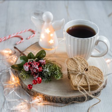 Tahta tezgahta bir fincan kahve, iple bağlanmış zencefilli kurabiye, masanın üzerinde bir çelenk. Kırmızı böğürtlenli yapay ladin dalı. Noel 'de kahvaltı. İskandinav tarzı. Boşluğu kopyala