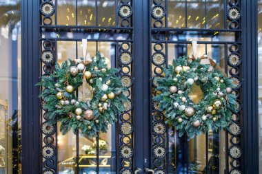 Noel çelengi, şeffaf bir kapıda asılı duran metal parçalı köknar dalları.