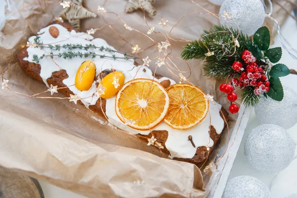 Geleneksel noel keki kuru turuncu takozlar, karanfil baharatı ve el işi kağıdında biberiye filizi ile süslenmiş.