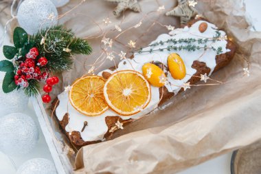 Geleneksel noel keki kuru turuncu takozlar, karanfil baharatı ve el işi kağıdında biberiye filizi ile süslenmiş.