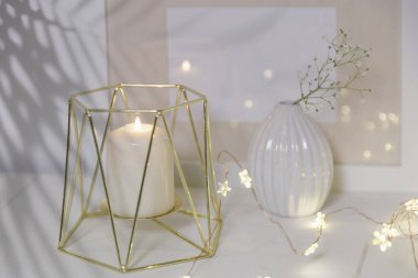 Yapay buzlu cam vazoda açılmamış iki sümbül. Modern İskandinav tarzında iç görünüş. Duvarda tuval ya da poster resmi var. Oturma odası, vazolu çekmeceler..