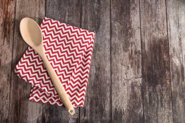 Mutfak havlusu peçetesi kahverengi ahşap masada. Üst Manzara. Maksimum keskinlik. Kırmızı ve beyaz zikzak şeklinde örülmüş peçete. Boşluğu kopyala