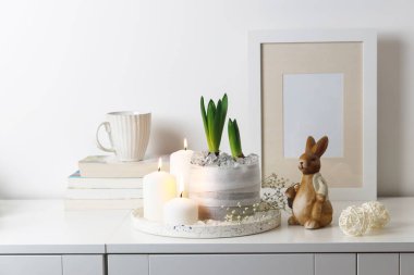 Tepside yanan mumlar, bir yığın kitap, bir kupa çay, duvarında iplik olan şişmemiş sümbüller. Paskalya odası dekorasyonu.