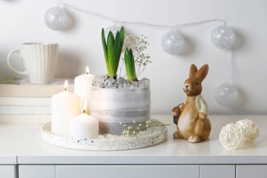 Tepside yanan mumlar, bir yığın kitap, bir kupa çay, duvarında iplik olan şişmemiş sümbüller. Paskalya odası dekorasyonu.