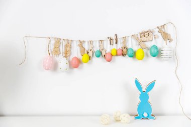 İç kısmın bir parçası. Paskalya için dekore edilmiş çocuk odası. Duvardaki kartondan kesilmiş plastik yumurta ve tavşanlardan oluşan bir çelenk. Tahta mavi tavşanlar. Mesajın için yer aç. Paskalya kartı.
