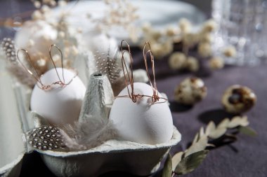Paskalya konsepti. Bakır kablo kulaklı beyaz bir yumurta ve kutuda uyuyan boyalı bir tavşan yüzü. Keklik yumurtası ve tüyleri..