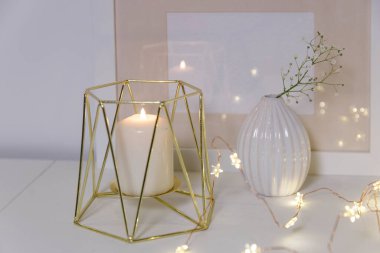 Yapay buzlu cam vazoda açılmamış iki sümbül. Modern İskandinav tarzında iç görünüş. Duvarda tuval ya da poster resmi var. Oturma odası, vazolu çekmeceler..