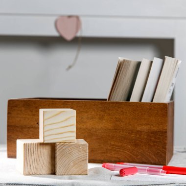 Kitaplarla dolu ahşap bir kap, masada beyaz bir şöminenin arka planında üç küp. Mesaj için yer. Sevgililer Günü