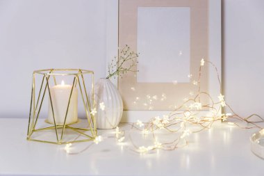 Yapay buzlu cam vazoda açılmamış iki sümbül. Modern İskandinav tarzında iç görünüş. Duvarda tuval ya da poster resmi var. Oturma odası, vazolu çekmeceler..