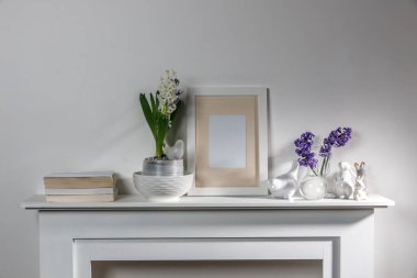 Tepside yanan mumlar, bir yığın kitap, bir kupa çay, duvarında iplik olan şişmemiş sümbüller. Paskalya odası dekorasyonu.