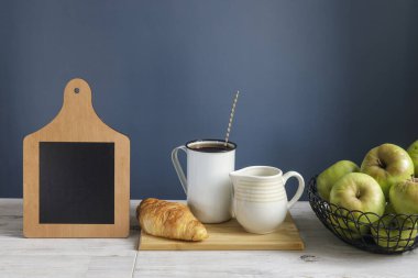 Tahta tabelalı kahve fincanı ve kruvasan. Tebeşir tahtası tasarım için arka plan oluşturur. Koyu mavi arka plan. Boşluğu kopyala