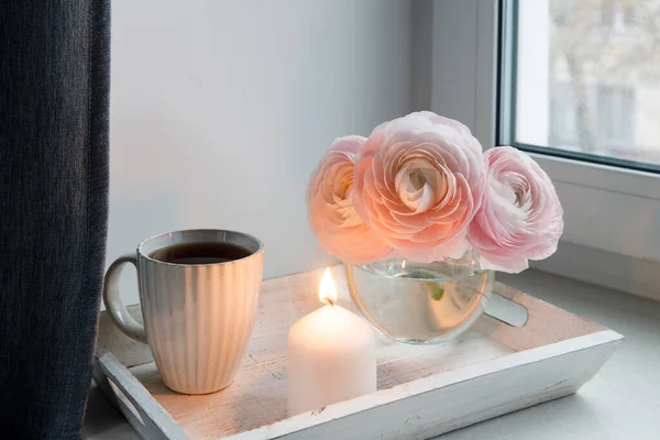 Три Блідо Рожеві Рунункули Прозорій Круглій Вазі Чашку Чаєм Свічкою — стокове фото