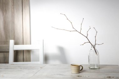 Cam bir vazoda patlamamış bir ıhlamur dalı ve masada küçük bir bej kahve fincanı var. İskandinav tarzı. Metnin için yer