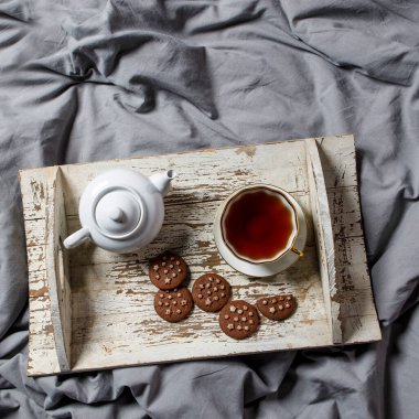 İç ve ev konforu. Üst Manzara. Bir fincan çay, bitkisel çaydanlık, yatağındaki tahta beyaz tepside şeker kasesi. Porselen bardak.