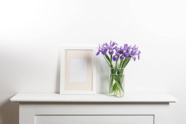 Vazoda süsen çiçekleri, çekmecede fotoğraf çerçeveleri.