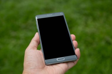 Elinde yeşil arkaplan olan akıllı telefon
