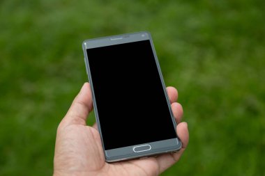 Elinde yeşil arkaplan olan akıllı telefon