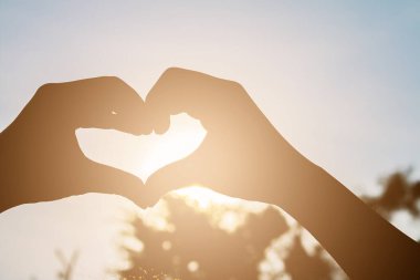 Aşk biçimli el silueti günbatımı arka planında