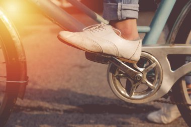 Kot giyen ve beyaz ayakkabı giyen bir kadın parkta bisiklet sürüyor.