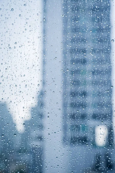 近代的なオフィスビルの背景を持つ汚れたガラス窓に雨の抽象的なイメージが落ちる — ストック写真