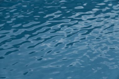 Mavi yüzme havuzu kenarında su dalgalanması var.