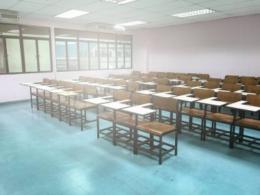 Sınıfın arka planında tahta sandalyeler var.