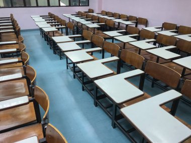 Sınıfın arka planında tahta sandalyeler var.