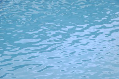 Mavi yüzme havuzu kenarında su dalgalanması var.